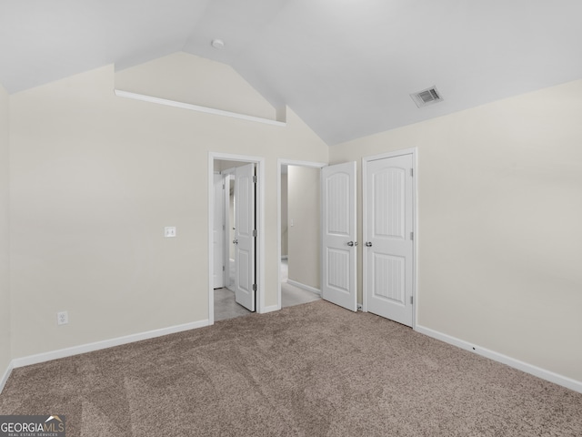 unfurnished bedroom featuring light carpet, vaulted ceiling, and a closet