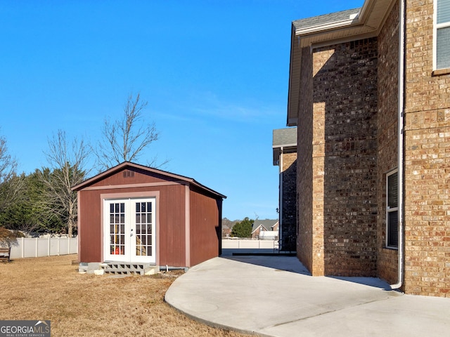 view of property exterior with french doors, an outdoor structure, and a patio area