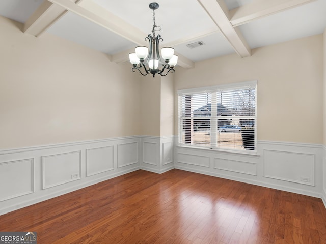 spare room with coffered ceiling, wood-type flooring, beam ceiling, and a chandelier