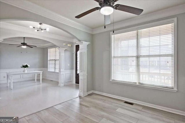 unfurnished dining area with ornate columns, ornamental molding, ceiling fan, and light hardwood / wood-style flooring