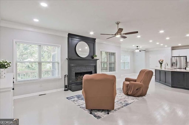 living room featuring a brick fireplace, ornamental molding, and sink