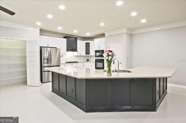 kitchen with a large island with sink, sink, white cabinets, and black appliances