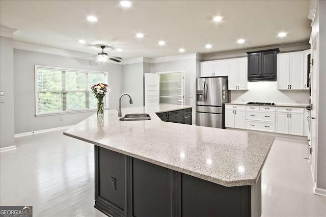 kitchen with a large island, sink, white cabinetry, light stone countertops, and stainless steel fridge with ice dispenser