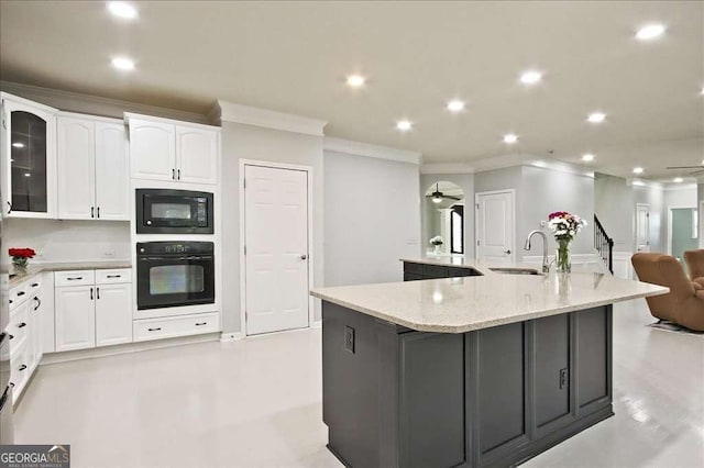 kitchen with sink, black appliances, white cabinets, and a spacious island