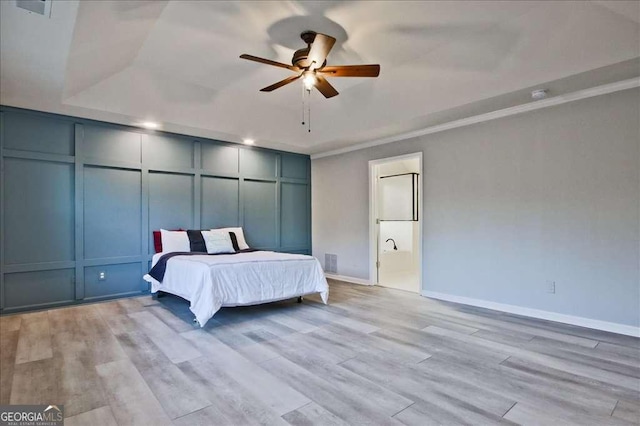 bedroom featuring crown molding, ceiling fan, a raised ceiling, and light hardwood / wood-style floors