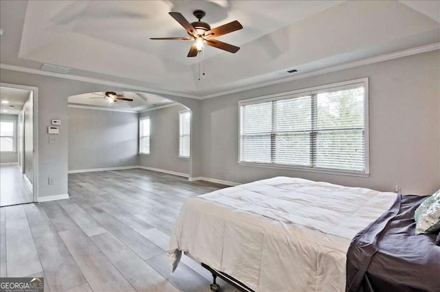 bedroom featuring crown molding, ceiling fan, a raised ceiling, and light hardwood / wood-style floors