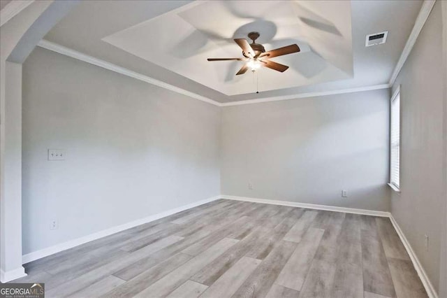 spare room featuring ceiling fan, ornamental molding, a raised ceiling, and light wood-type flooring