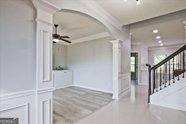 entrance foyer featuring crown molding, decorative columns, light hardwood / wood-style floors, and ceiling fan