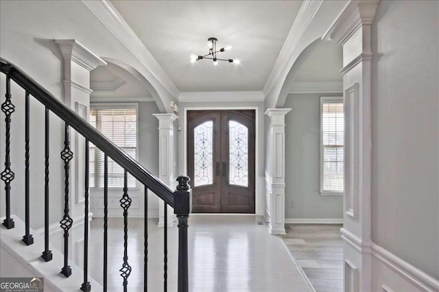 entrance foyer with an inviting chandelier, crown molding, french doors, and ornate columns