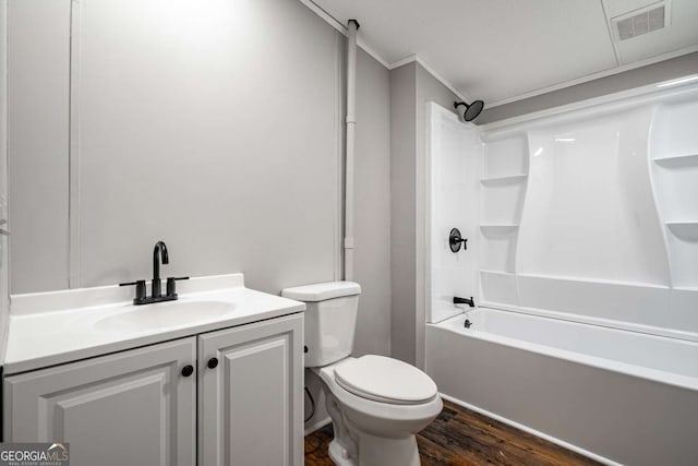 full bathroom featuring hardwood / wood-style floors, vanity, shower / bathing tub combination, ornamental molding, and toilet