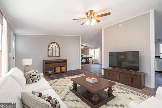 living room with crown molding, vaulted ceiling, dark hardwood / wood-style floors, and ceiling fan