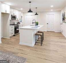 kitchen featuring a kitchen island, lofted ceiling with beams, a breakfast bar area, white cabinets, and light hardwood / wood-style floors