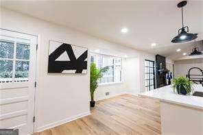 kitchen featuring pendant lighting, appliances with stainless steel finishes, a kitchen island with sink, a kitchen breakfast bar, and white cabinets