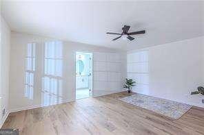 living room with ceiling fan, a large fireplace, beam ceiling, and light hardwood / wood-style floors