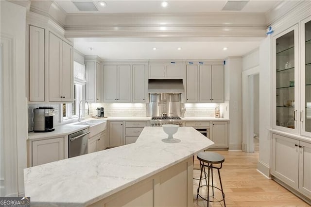 kitchen featuring crown molding, a sink, a kitchen bar, dishwasher, and ventilation hood