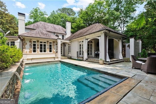 back of property featuring an outbuilding, a patio, and pool water feature