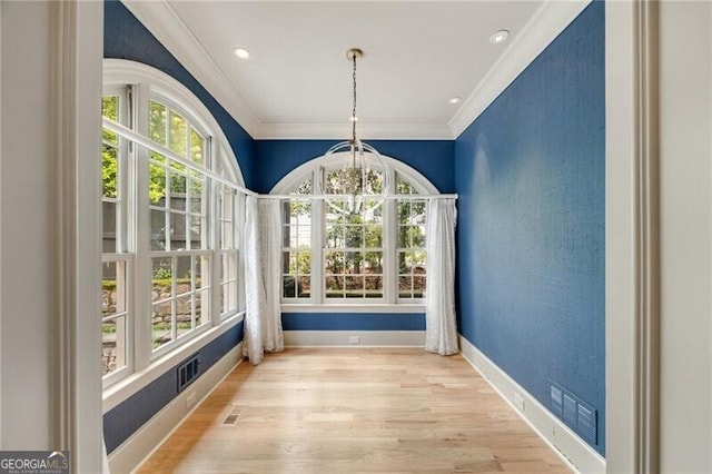 unfurnished dining area with a chandelier, visible vents, baseboards, ornamental molding, and wood finished floors