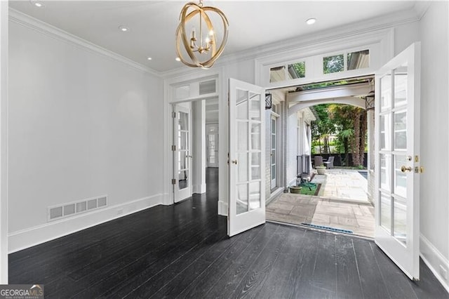 foyer featuring crown molding, a notable chandelier, dark hardwood / wood-style floors, and french doors