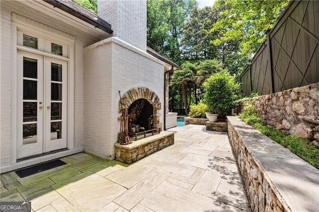 view of patio with an outdoor stone fireplace and french doors