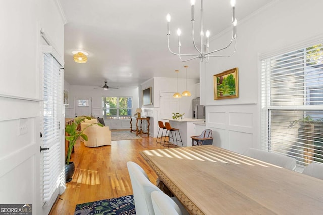 dining area featuring ceiling fan with notable chandelier, crown molding, and light hardwood / wood-style floors