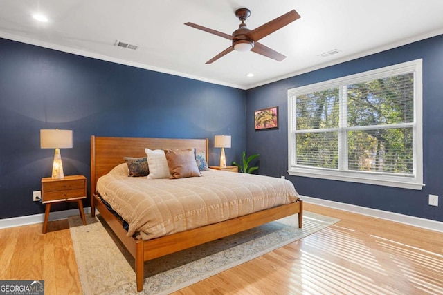 bedroom with crown molding, light wood-type flooring, and ceiling fan