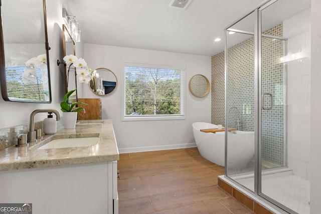 bathroom featuring vanity, wood-type flooring, and plus walk in shower