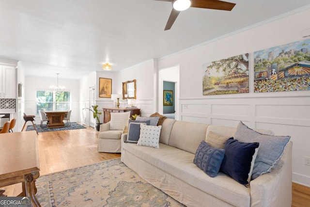 living room featuring crown molding, ceiling fan with notable chandelier, and light wood-type flooring