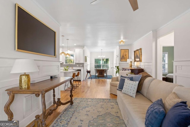 living room with crown molding, light hardwood / wood-style floors, and a notable chandelier