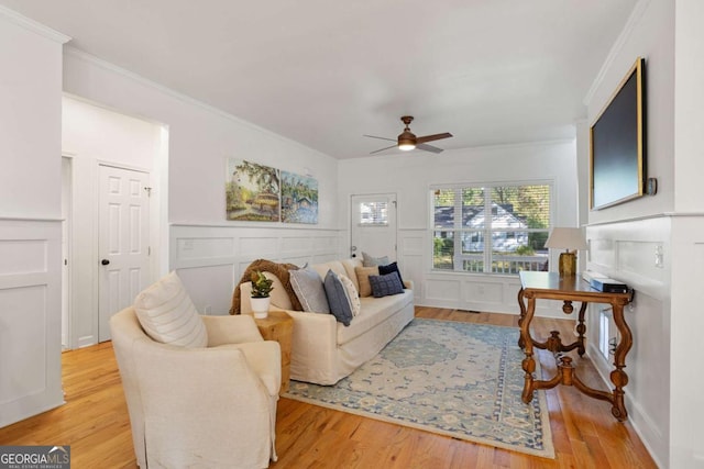 living room featuring crown molding, ceiling fan, and light wood-type flooring