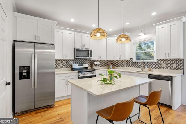 kitchen with appliances with stainless steel finishes, sink, hanging light fixtures, and white cabinets