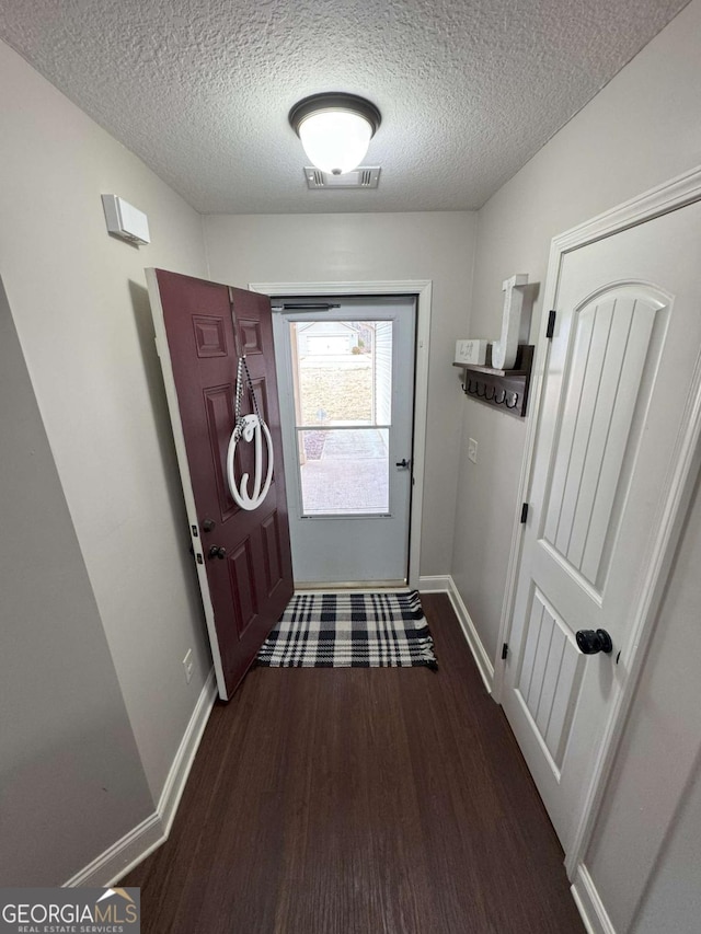 doorway featuring dark hardwood / wood-style floors and a textured ceiling