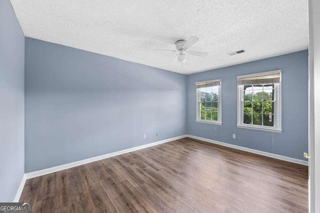 empty room with ceiling fan, wood-type flooring, and a textured ceiling