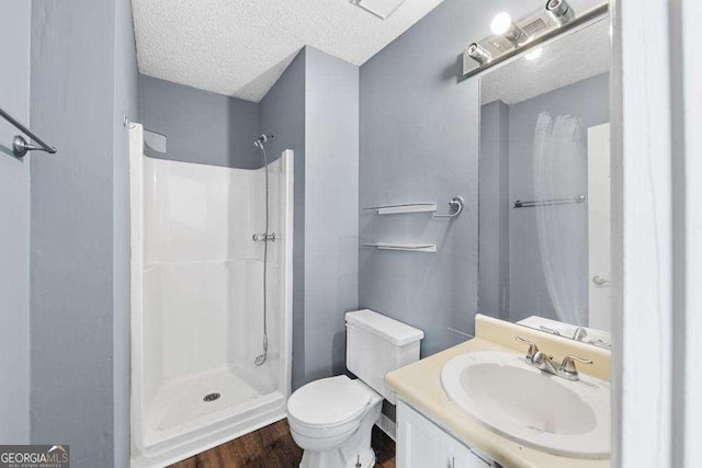 bathroom with hardwood / wood-style floors, vanity, a textured ceiling, a shower, and toilet