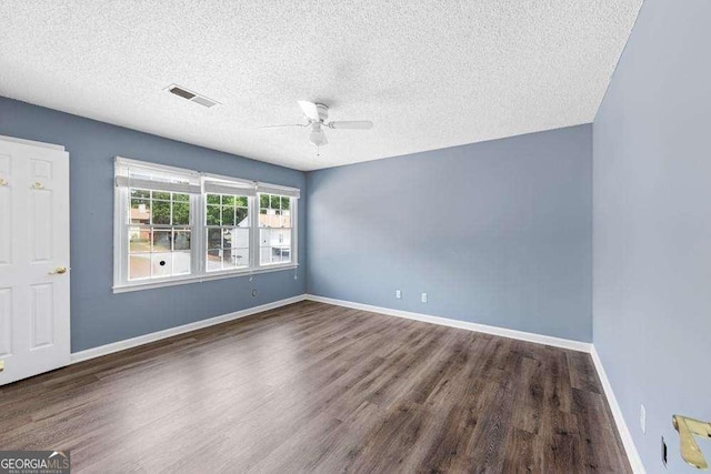 empty room featuring ceiling fan, dark wood-type flooring, and a textured ceiling