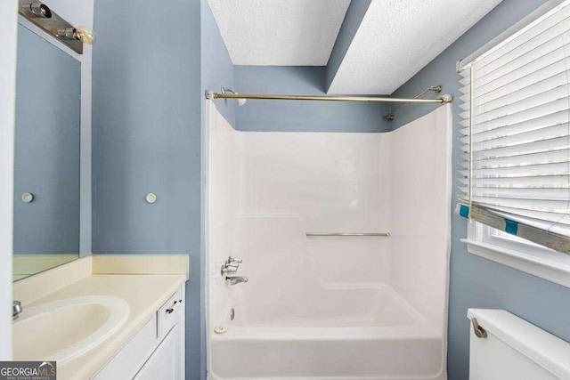 full bathroom featuring vanity, bathing tub / shower combination, a textured ceiling, and toilet