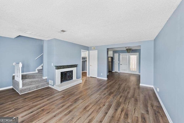 unfurnished living room with a textured ceiling, a fireplace, and dark hardwood / wood-style flooring