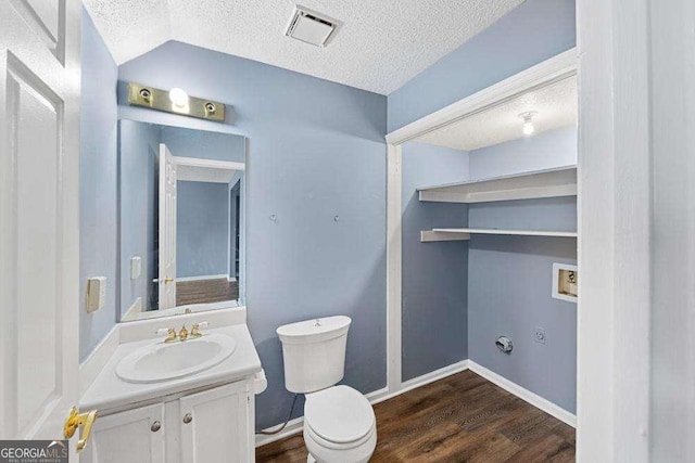 bathroom with vanity, vaulted ceiling, toilet, and a textured ceiling