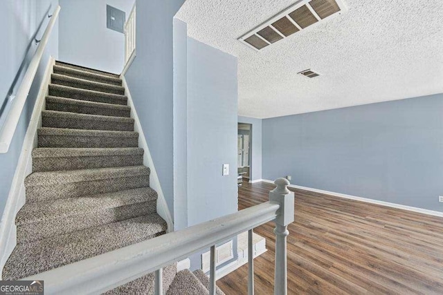 stairway with hardwood / wood-style flooring and a textured ceiling