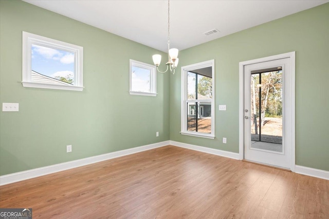 empty room featuring a chandelier and light wood-type flooring