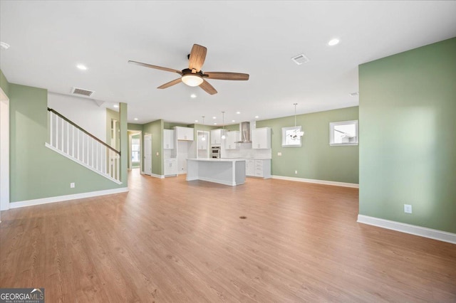 unfurnished living room featuring ceiling fan and light hardwood / wood-style flooring