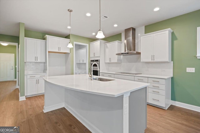 kitchen with backsplash, wall chimney exhaust hood, sink, and white cabinets