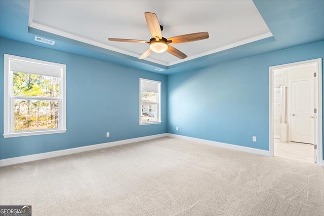 carpeted empty room with ceiling fan and a raised ceiling