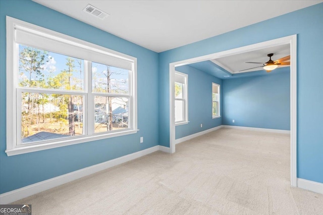 carpeted spare room featuring ceiling fan and a healthy amount of sunlight