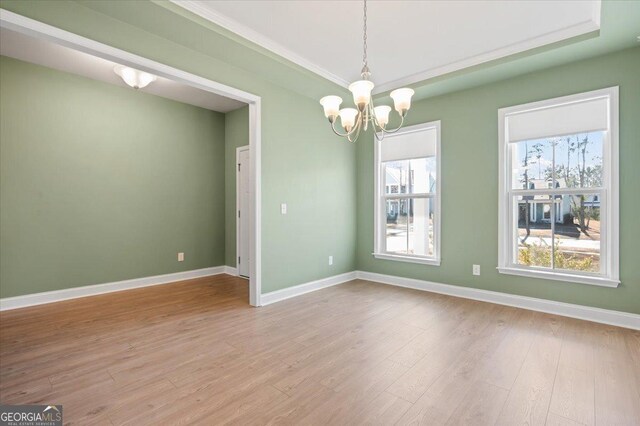 spare room with an inviting chandelier, a healthy amount of sunlight, and light wood-type flooring