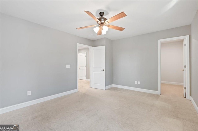 unfurnished bedroom featuring a spacious closet, light colored carpet, and ceiling fan