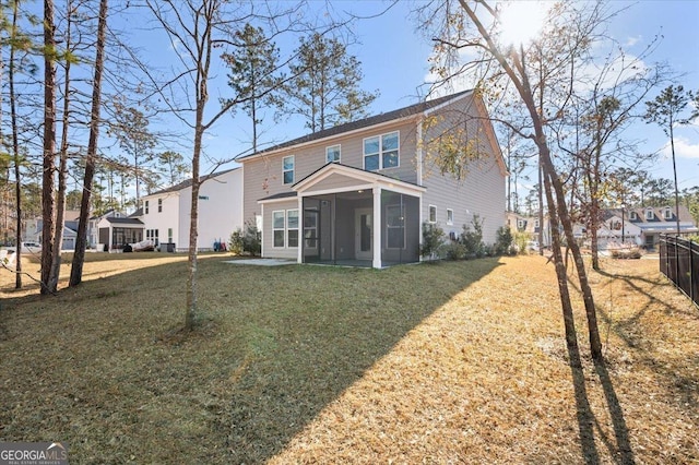 rear view of house with a sunroom and a lawn