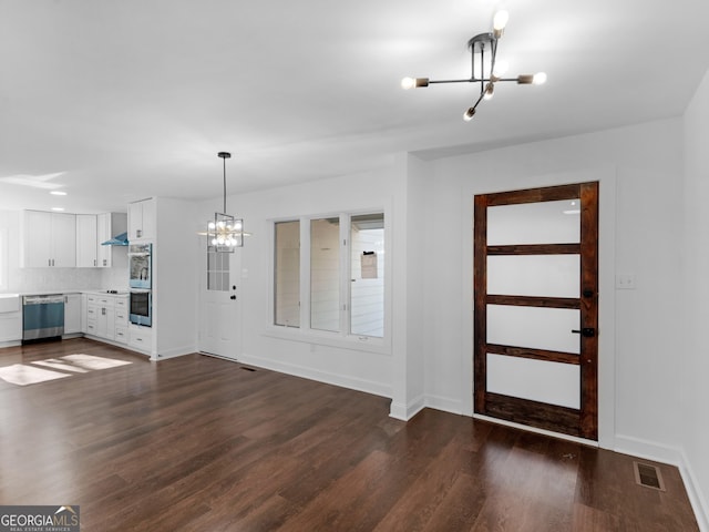 entrance foyer featuring dark wood-type flooring and a notable chandelier