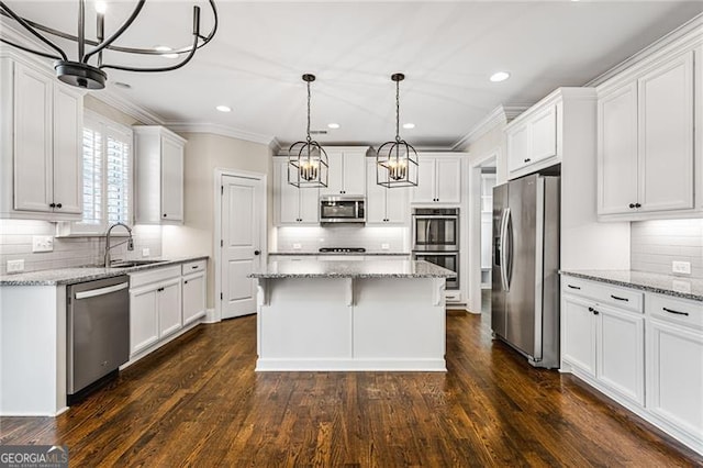 kitchen with light stone counters, decorative light fixtures, stainless steel appliances, white cabinets, and a kitchen island