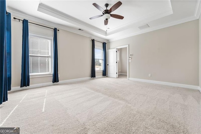 empty room featuring ornamental molding, a raised ceiling, light carpet, and baseboards