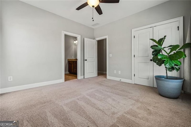 unfurnished bedroom with baseboards, a ceiling fan, connected bathroom, light colored carpet, and a closet